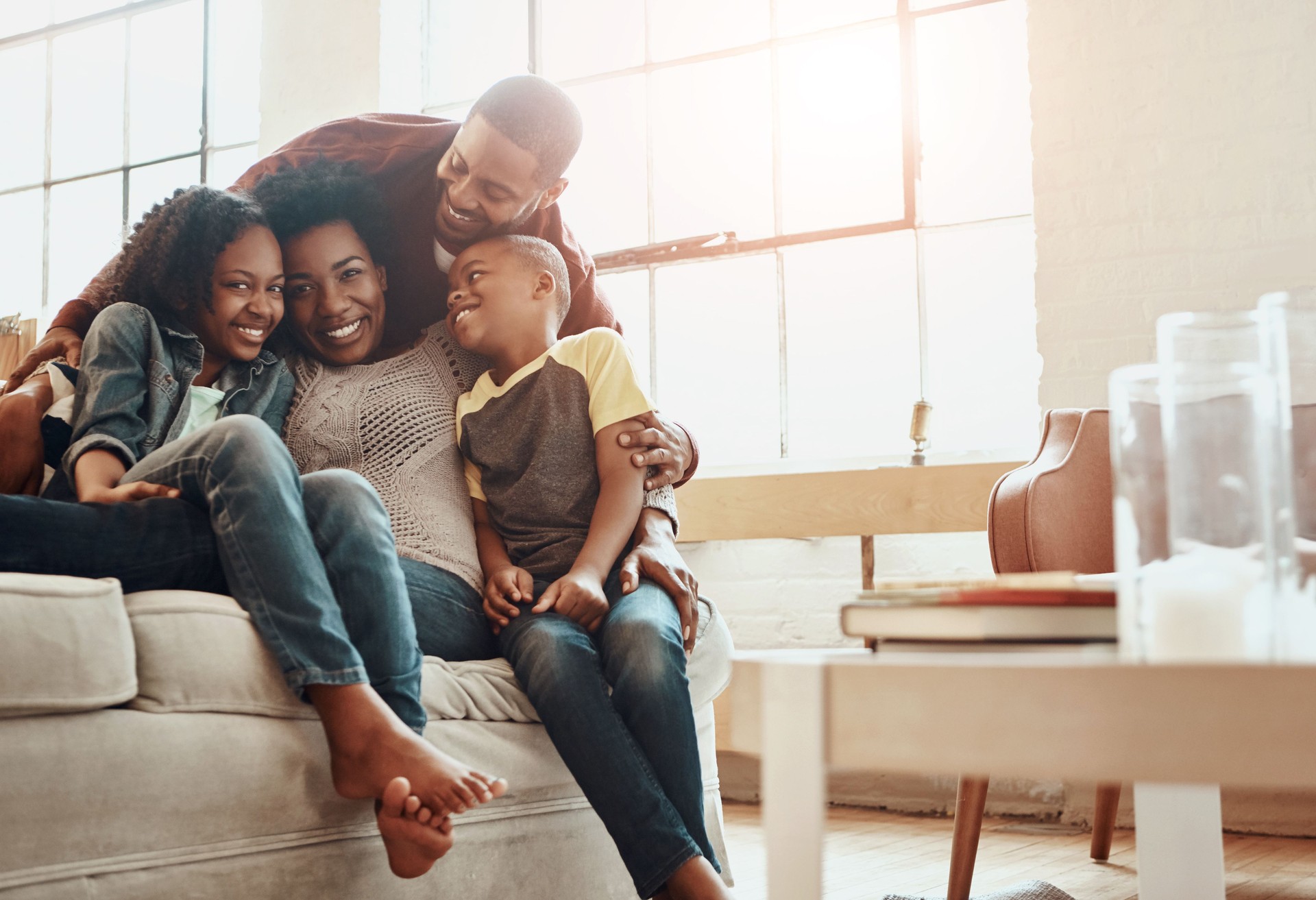 Happy, portrait and black family on sofa in home for hugging, love and care on fathers day for celebration. Smile, bonding and African kids with mom and day relaxing together in living room at house.