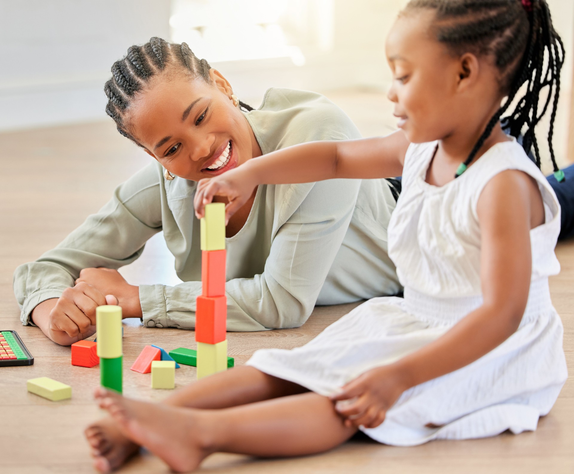 Family on the floor, mother and girl with blocks, playful and fun with happiness, weekend break and relaxing. Mama, apartment and kid with child development, home and building tower with wooden toys